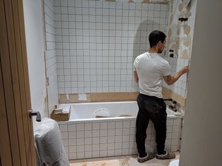 Installing white grid tiling on bathroom wall