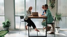 A couple sits at a tall table with their financial adviser