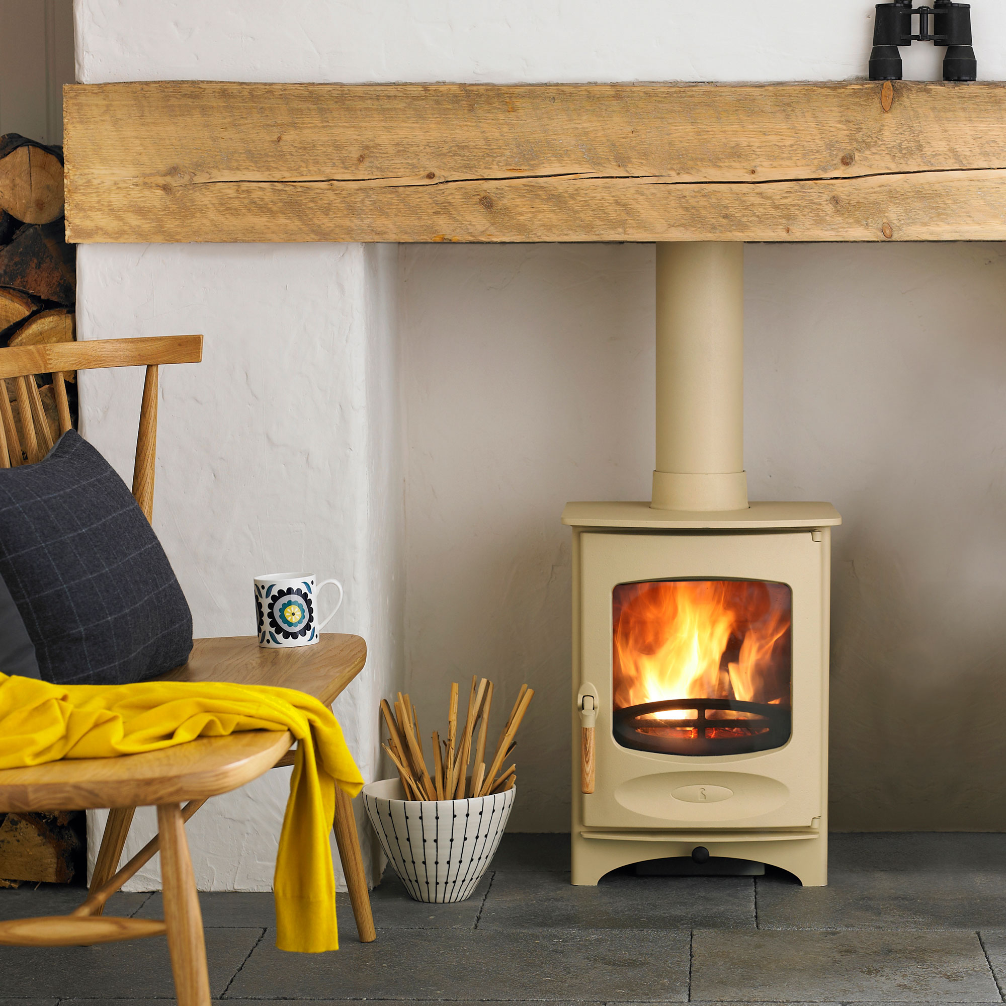 small cream log burner in inglenook fireplace with slate hearth