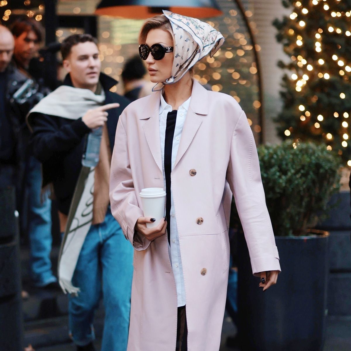 bella hadid wears a head scarf, pink coat, black capri pants, and black ballet flats.