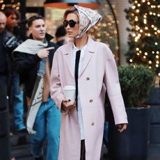 bella hadid wears a head scarf, pink coat, black capri pants, and black ballet flats.