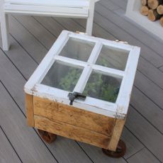 DIY wooden cold frame cloche with white painted window frame cover on wheels at RHS Chelsea Flower Show 2023