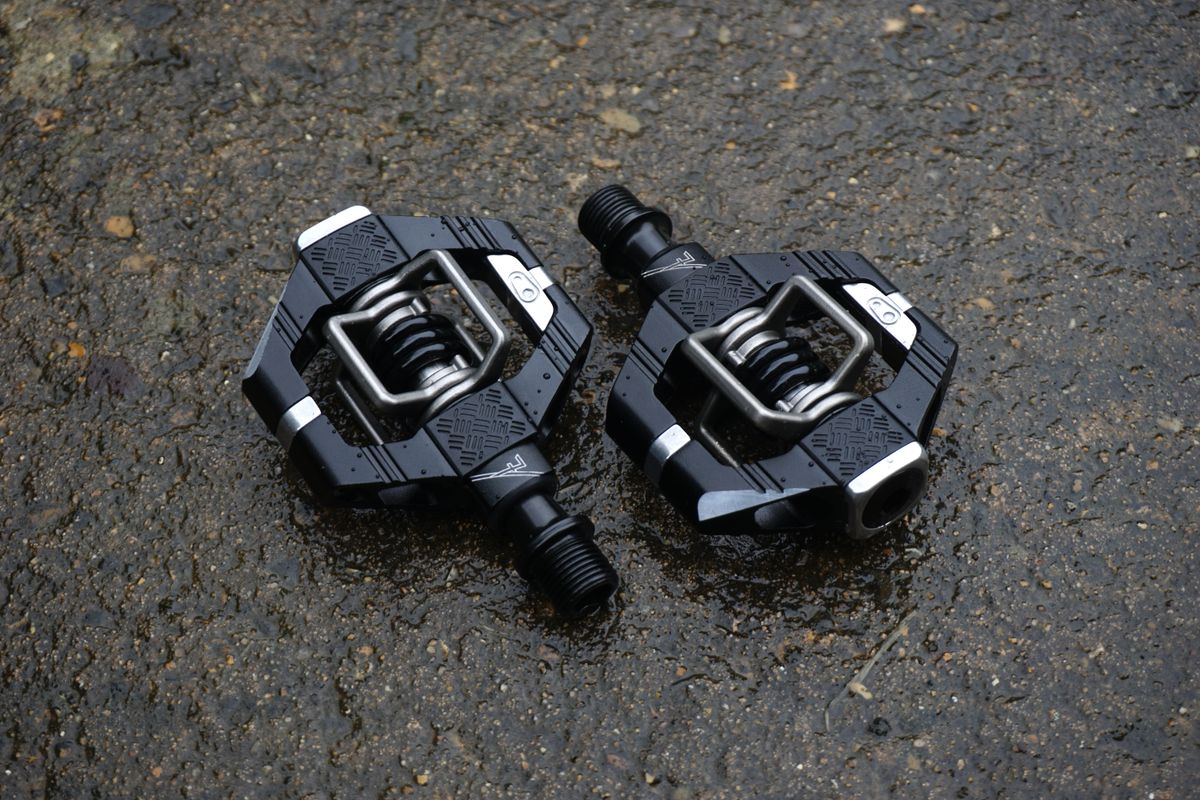 A pair of black gravel bike pedals on tarmac