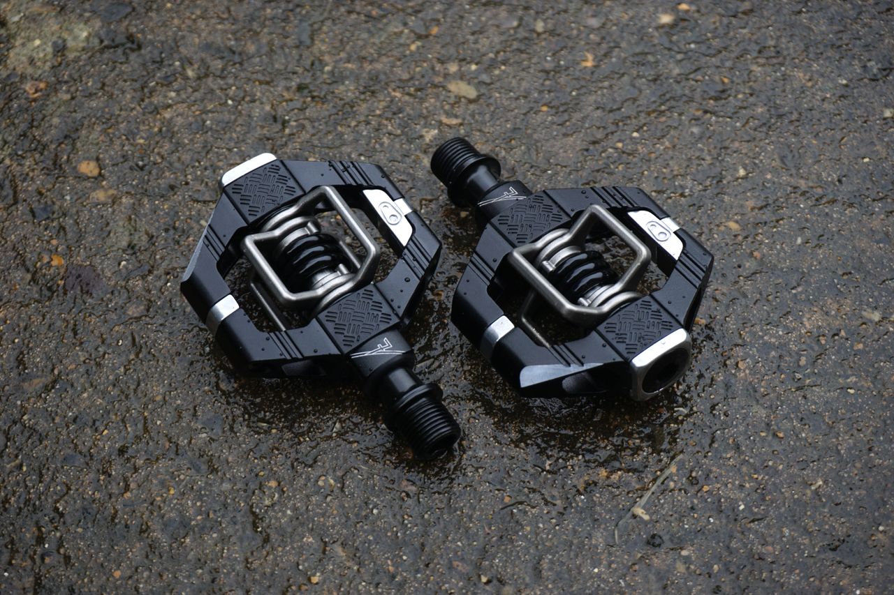 A pair of black gravel bike pedals on tarmac