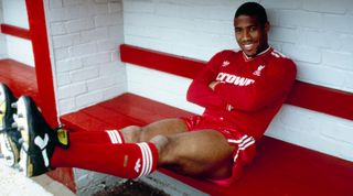 LIVERPOOL, ENGLAND - JUNE 09: John Barnes poses in the home team dug out for an official photograph shortly after signing for Liverpool from Watford at Anfield on June 09, 1987 in Liverpool, England. (Photo by Liverpool FC/Liverpool FC via Getty Images)