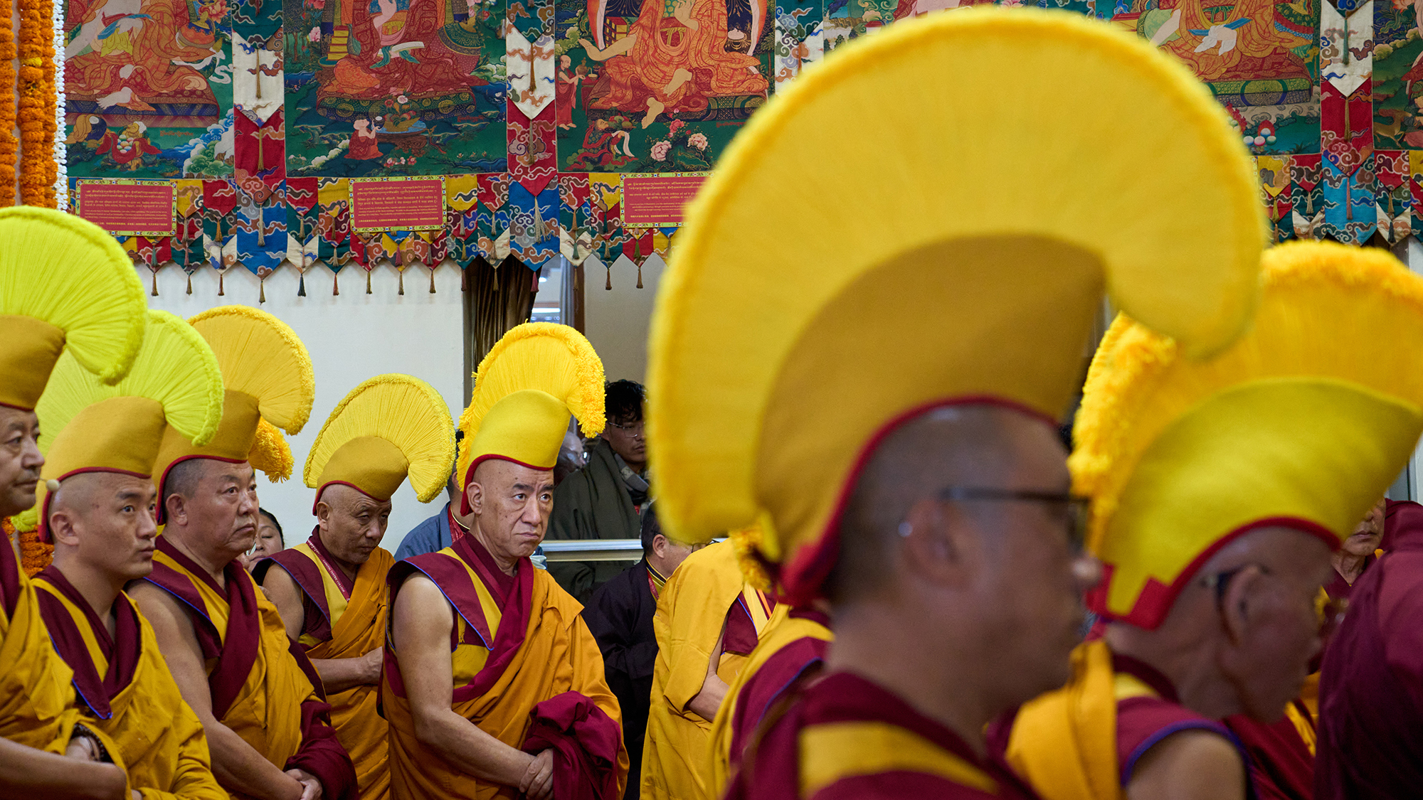Tibetan Buddhist monks in ceremonial Gelugpa hats wait to welcome the Dalai Lama to an event at the Tsuglagkhang Temple in Dharamshala, India
