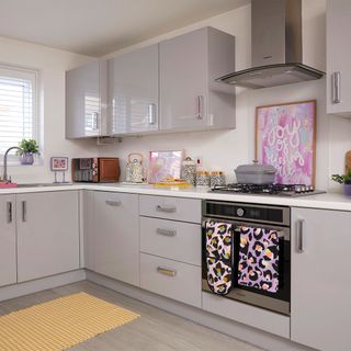 grey gloss kitchen with yellow rug and bright tea towel and oven glove