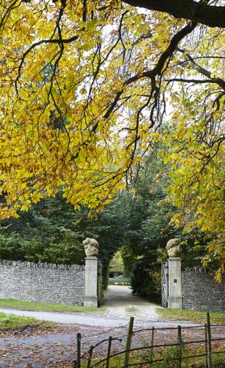autumn scene on a country lane with sculptures on manor house gateposts
