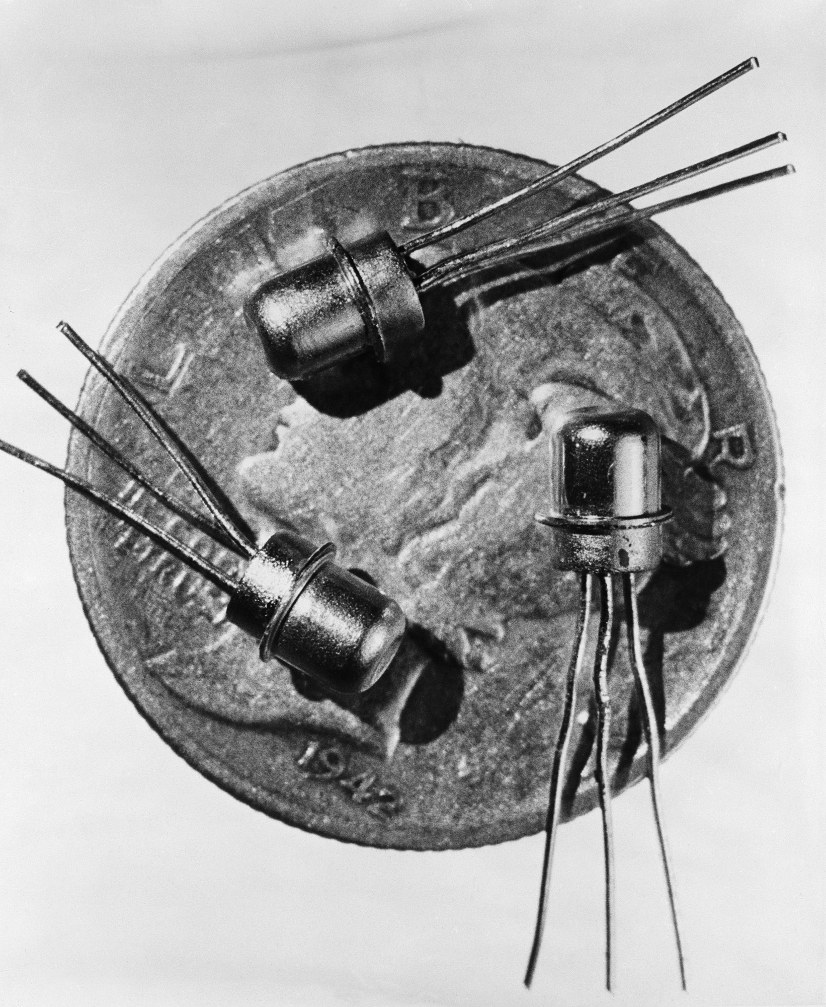 Three early transistor components placed on top of a coin to show their size