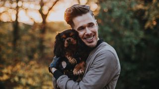 Cavalier King Charles spaniel being cuddled by man outside