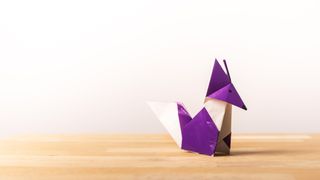 An origami purple fox on a wooden surface