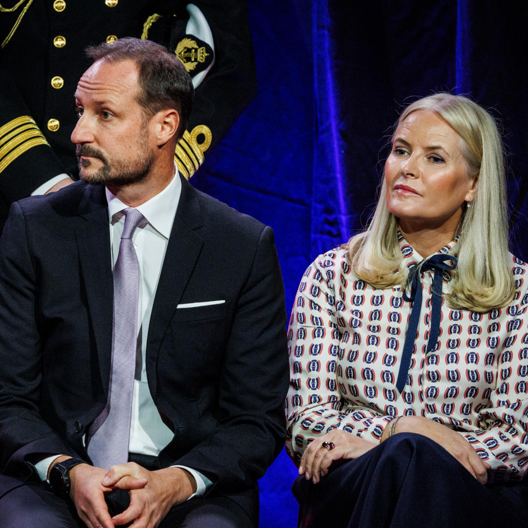 Crown Princess Mette-Marit sitting next to Crown Prince Haakon on a stage