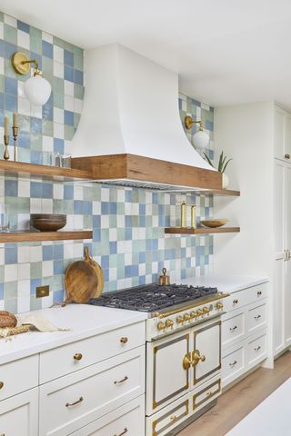 blue white and green tiled kitchen backsplash with open shelves and cream range cooker and white extractor hood
