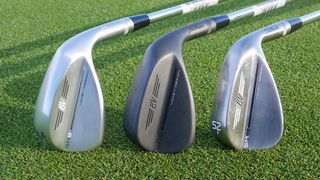 three titleist vokey sm9 wedges lying on the ground in chrome, black and steel finishes