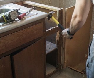 hand using tool to remove kitchen cupboard door