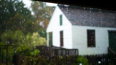 Rain falling in front of a white farmhouse
