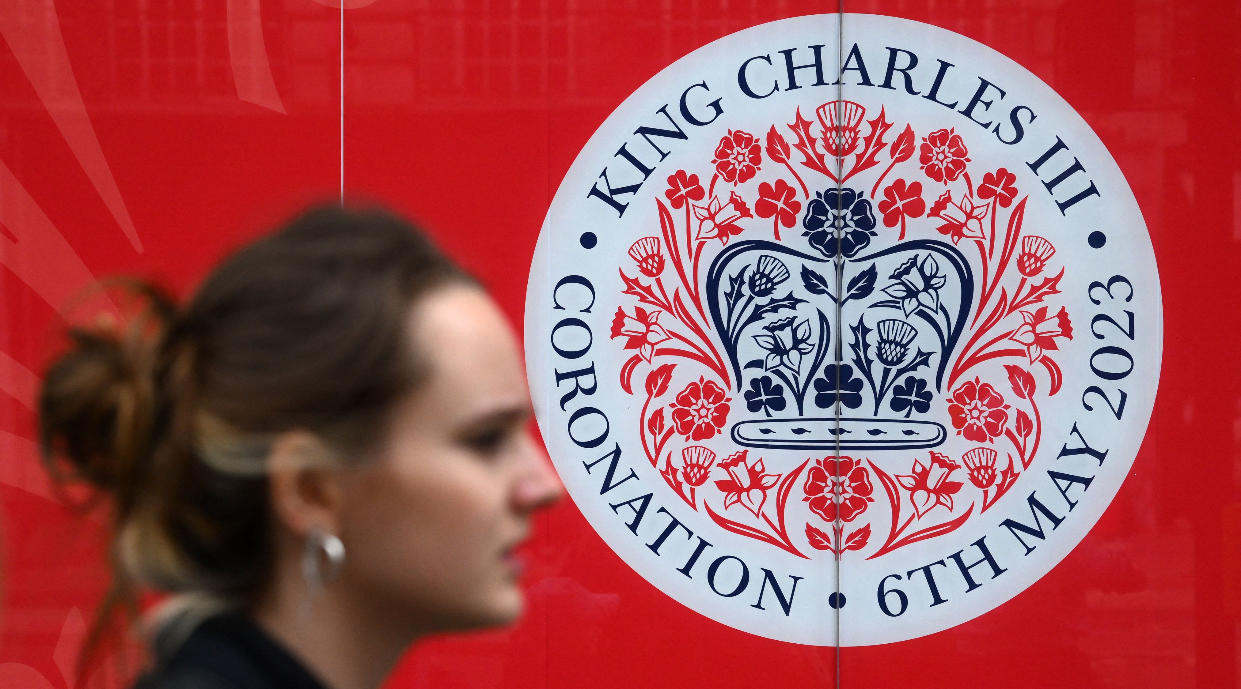 A pedestrian walks past an emblem commemorating the coronation of King Charles III on April 28, 2023 in London, United Kingdom.