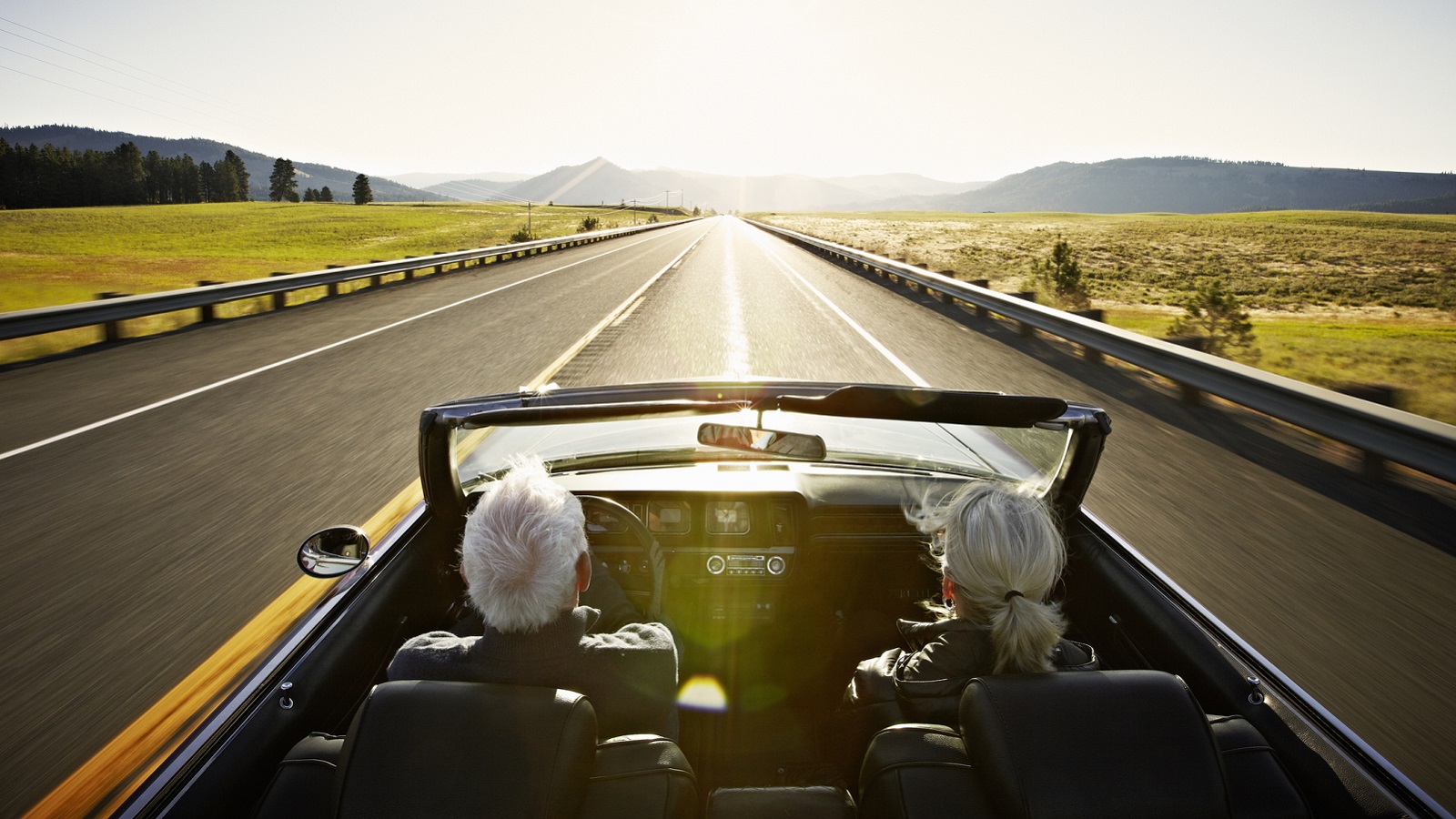 A rich older couple in a sports car.