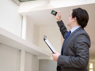 A building surveyor taking a photo of damp in a property