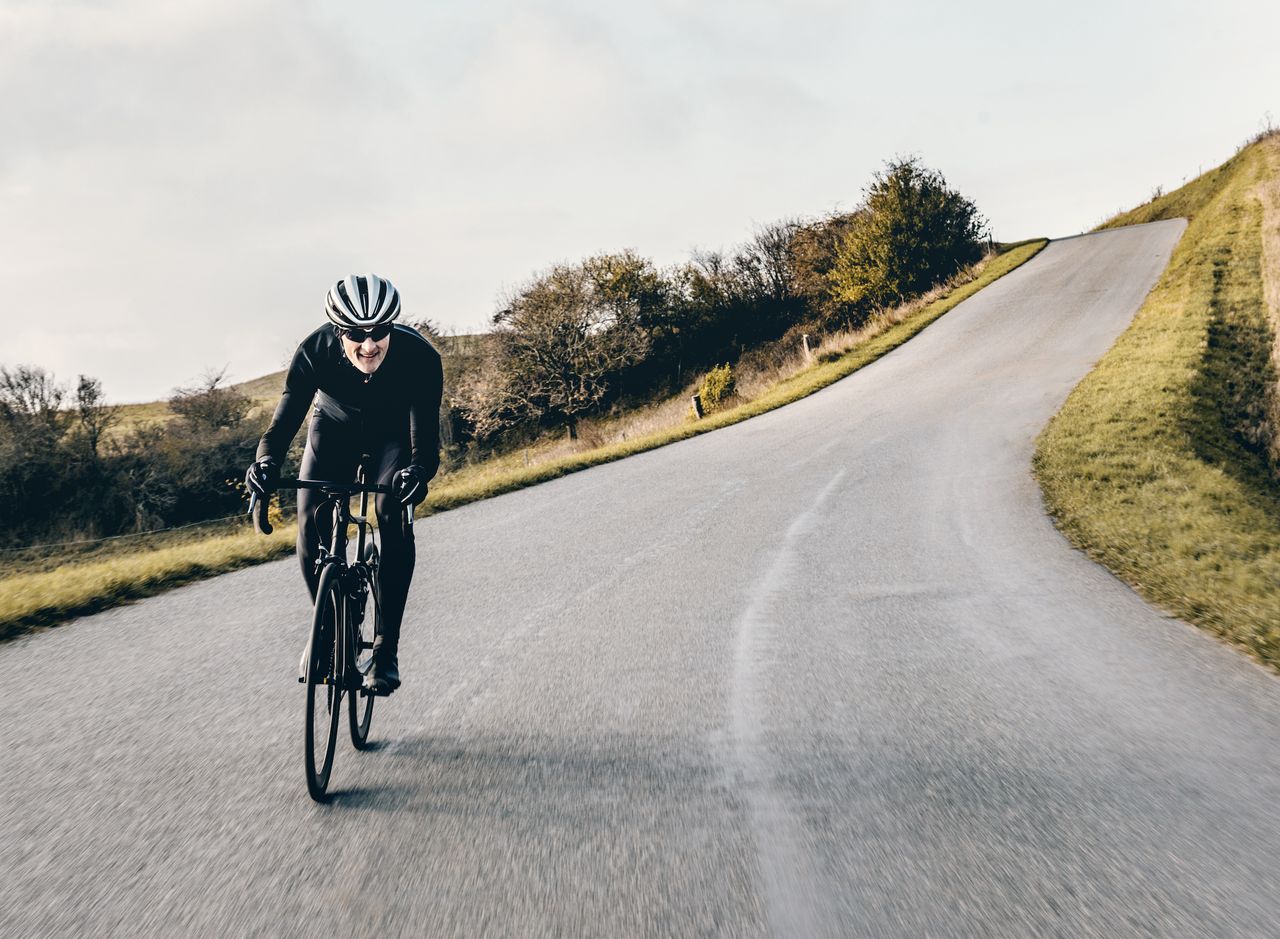 male cyclist riding downhill on the drops headwind