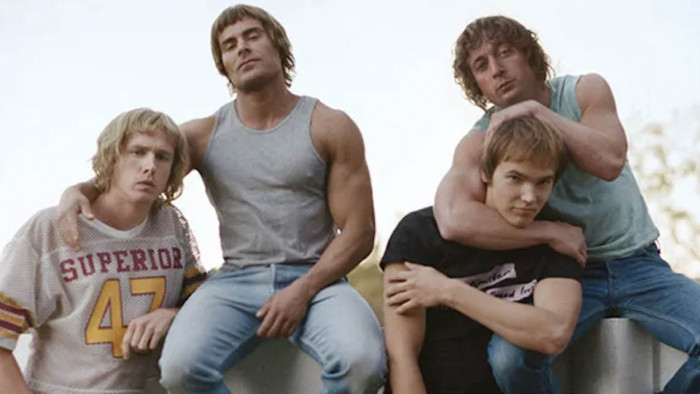 The cast of The Iron Claw sitting on a fence