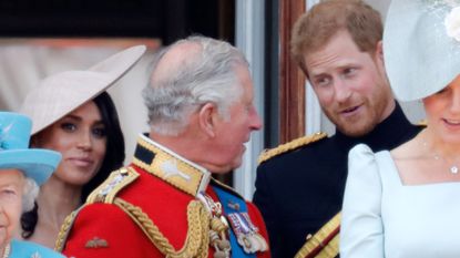 Prince Harry talks animatedly to King Charles with Meghan Markle in the background