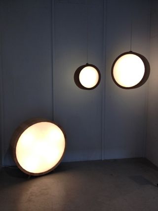 Three circular lanterns in different sizes. Two are hanging from the ceiling one is on the floor.