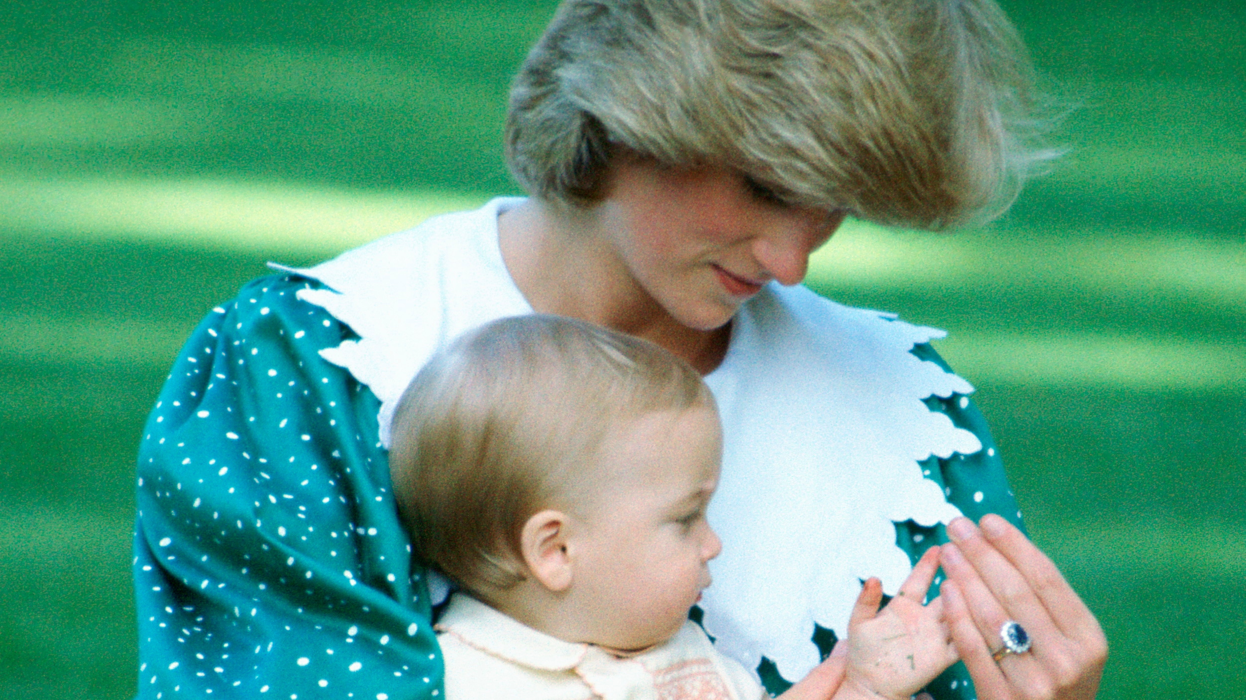 Princess Diana, wearing her engagement ring, sits with baby Prince William on her lap for an official photo in the gardens of Government House