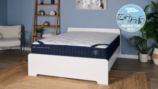 The DreamCloud Classic Hybrid mattress on a white wooden bedframe with a blue Tom's Guide Presidents' Day sales badge overlaid in the top right hand corner