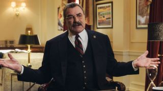 Tom Selleck sitting at a desk while playing Frank Reagan in Blue Bloods.