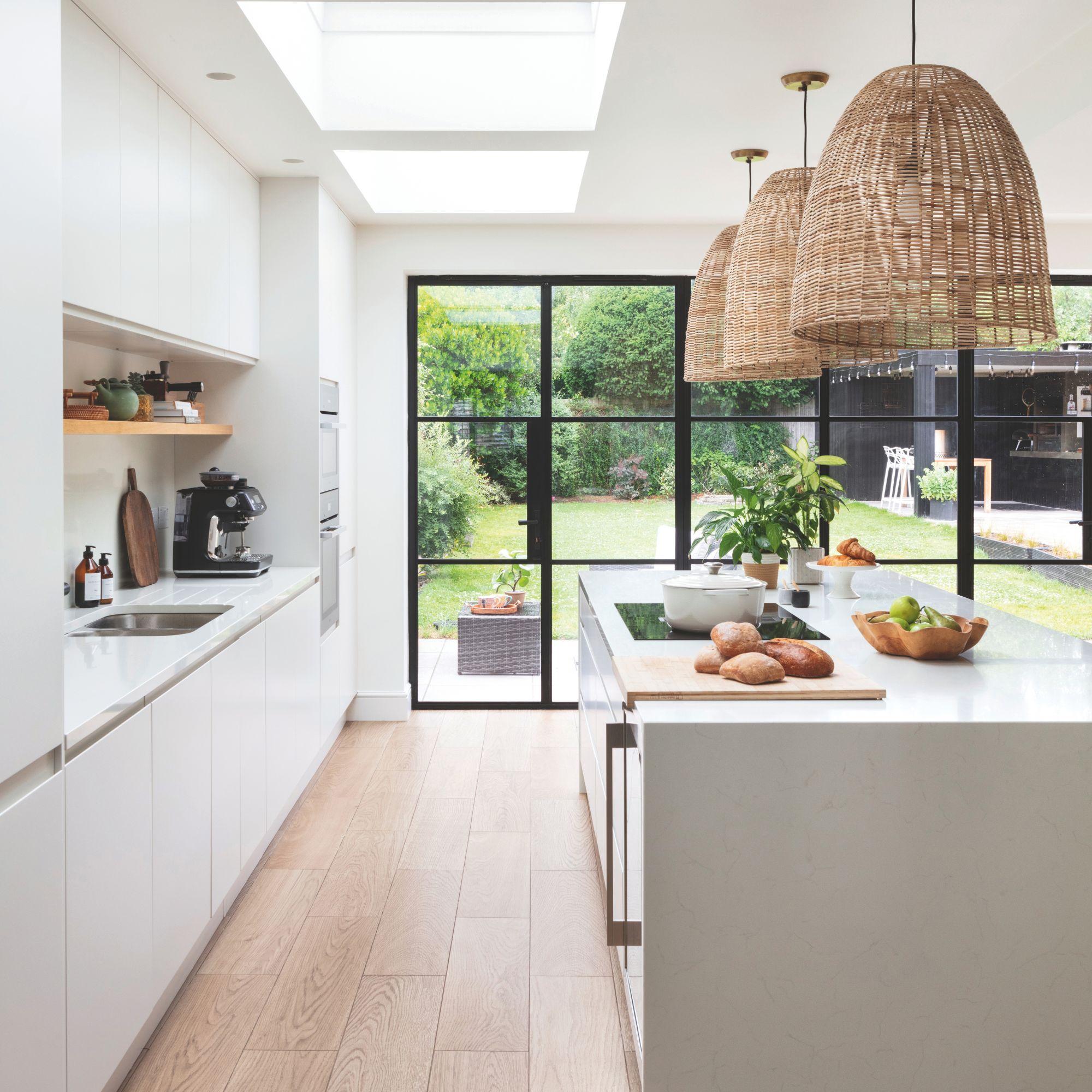 White kitchen with large crittal floor-to-ceiling glass doors, and white cabinets and island in the kitchen
