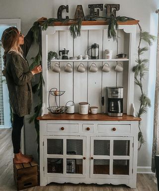 A DIY coffee bar setup created from thrifted furniture with white paint and accessories