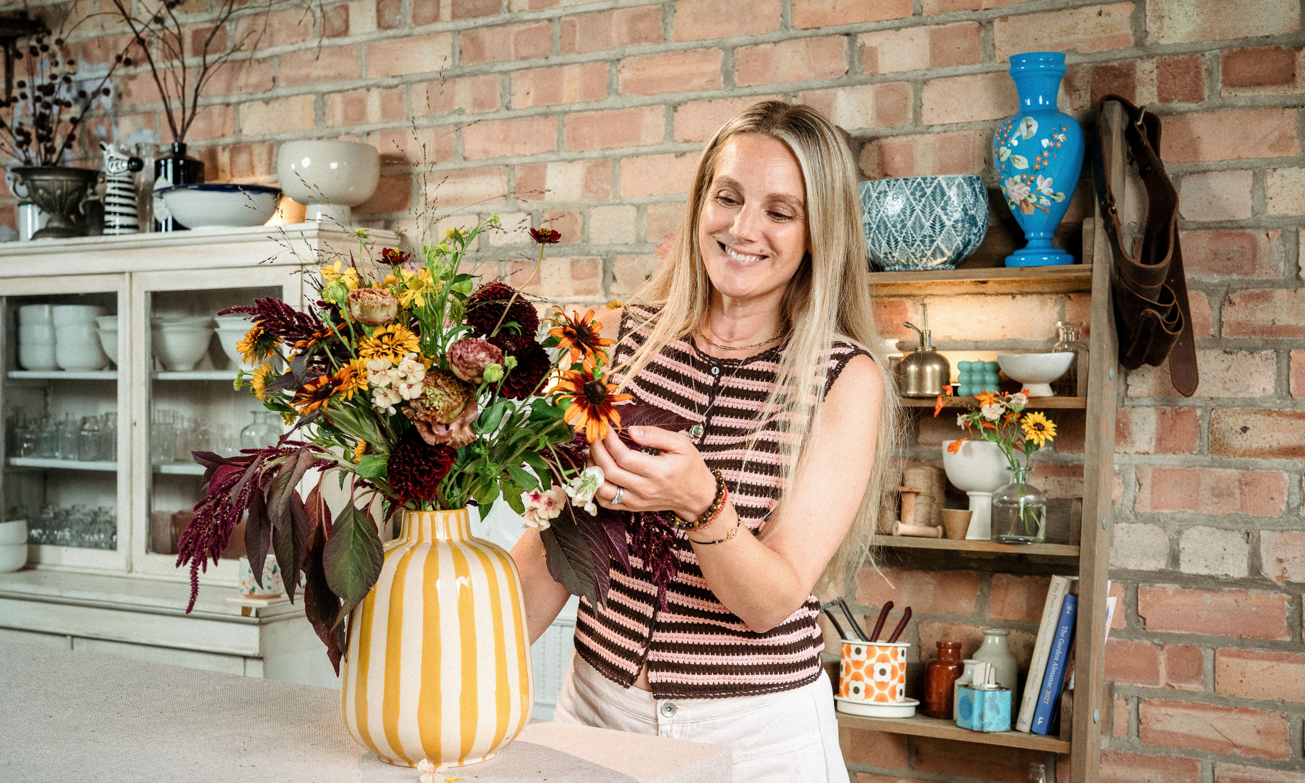 Woman stood next to vase of autumnal flowers