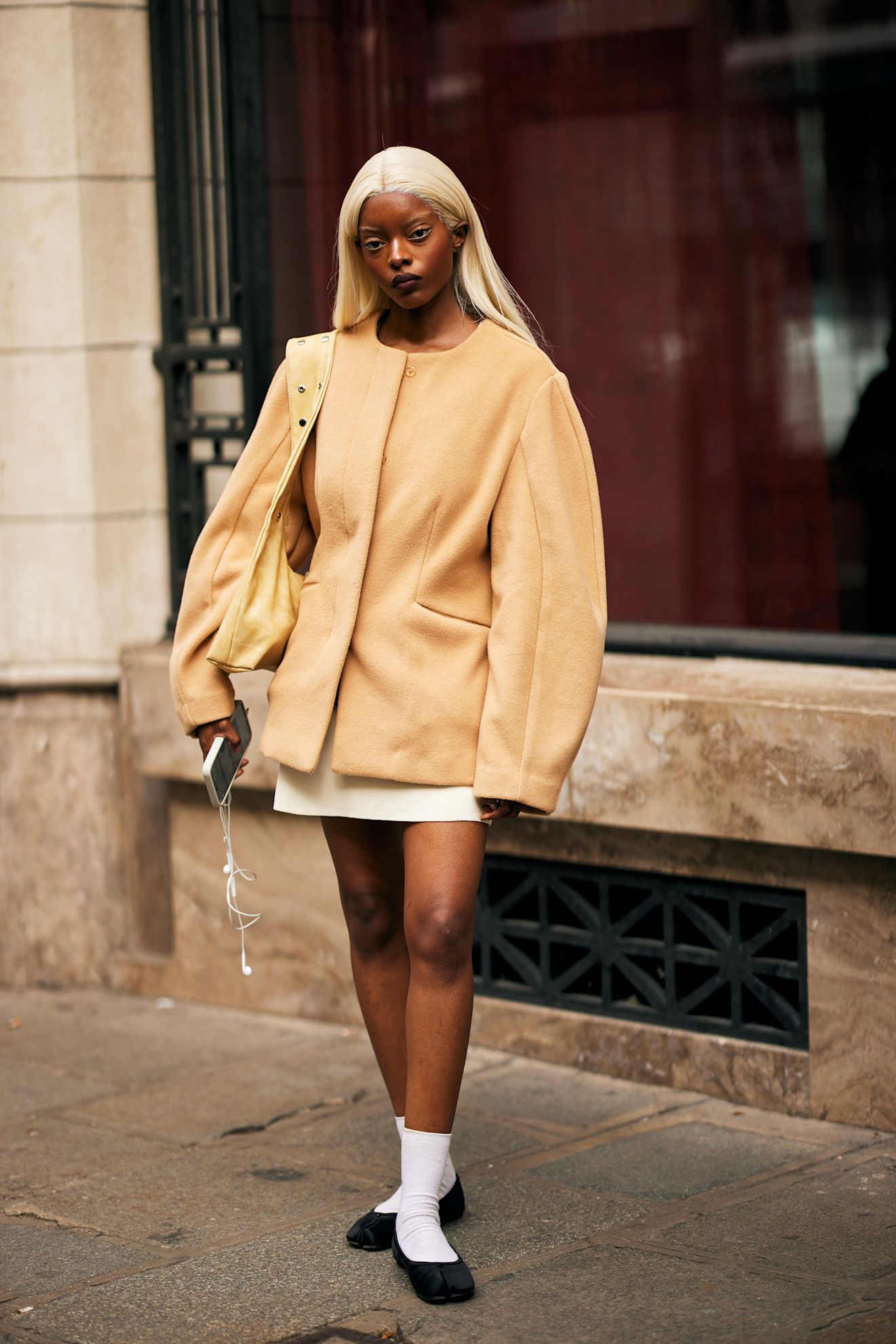 Woman in a yellow collarless jacket, a mini skirt, and black flats
