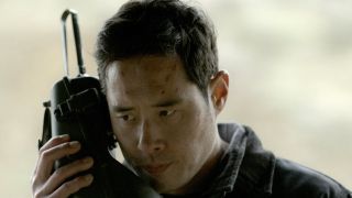 Raymond Lee holding a satellite phone in Quantum Leap as Dr. Ben Song