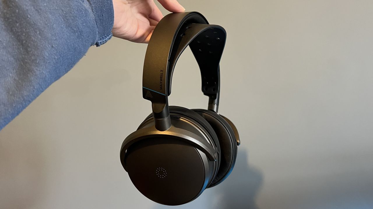 Audeze Maxwell 2 being held by the headstrap in front of a blue wall
