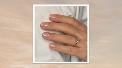 A close up of a hand wearing a gold and diamond engagement ring and with a very subtle and natural-looking French tip manicure, by nail artist Megan Rose/ in a beige and grey sunset-style template