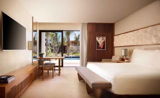 Nobu Hotel room with sliding door onto pool area, wooden console and large TV on wall
