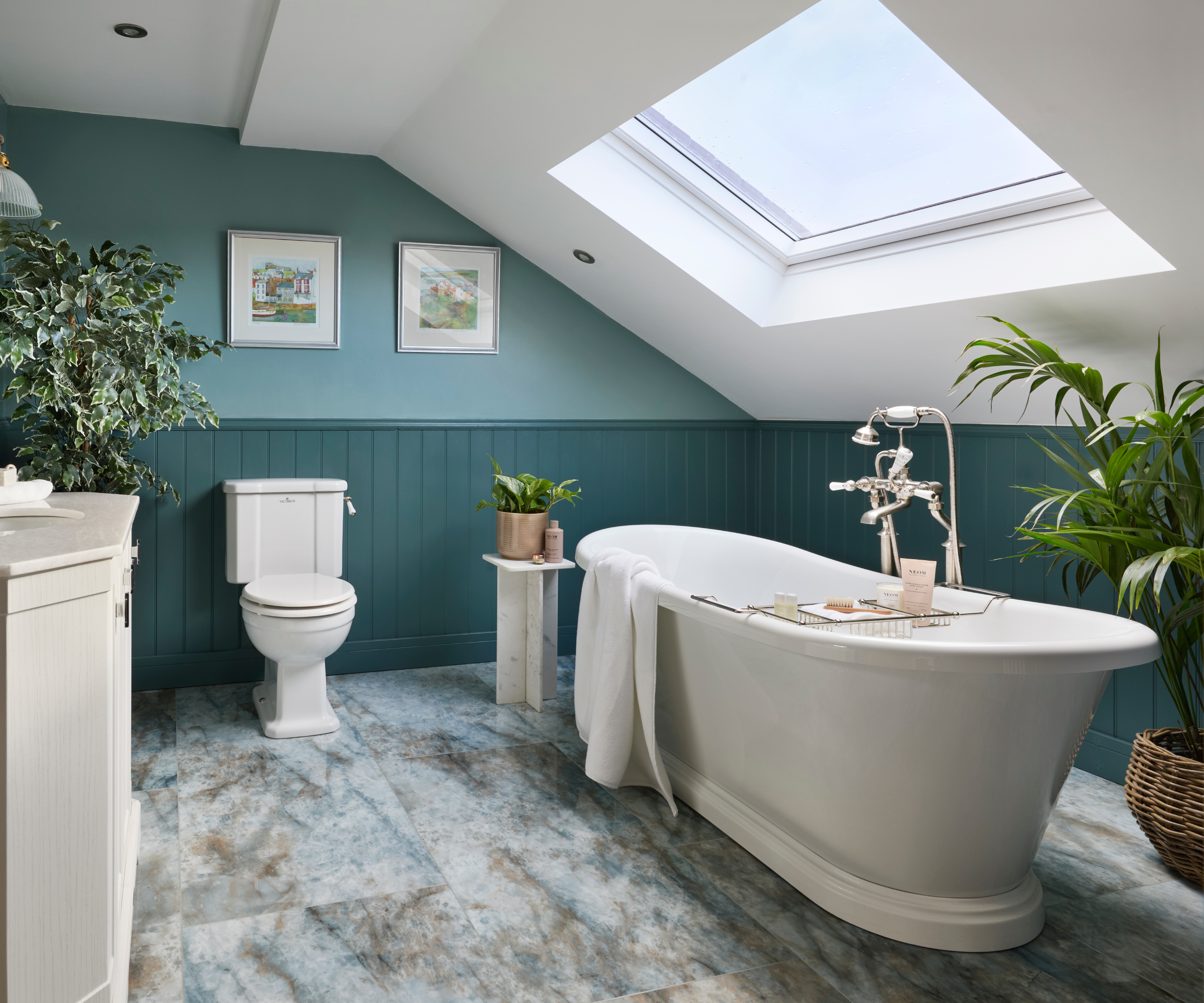 large bathroom with freestanding bath, skylight above bath, blue tiles, blue wall panelling