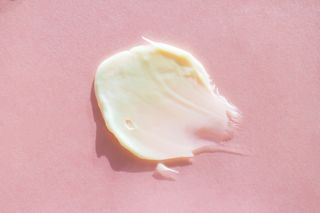 Smear of pastel beige body cream on light pink background. Concept of natural skin care cosmetic. Extreme close-up and flat lay style (Smear of pastel beige body cream on light pink background. Concept of natural skin care cosmetic. Extreme close-up a