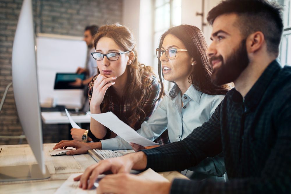 Man and two women collaborating in front of a computer