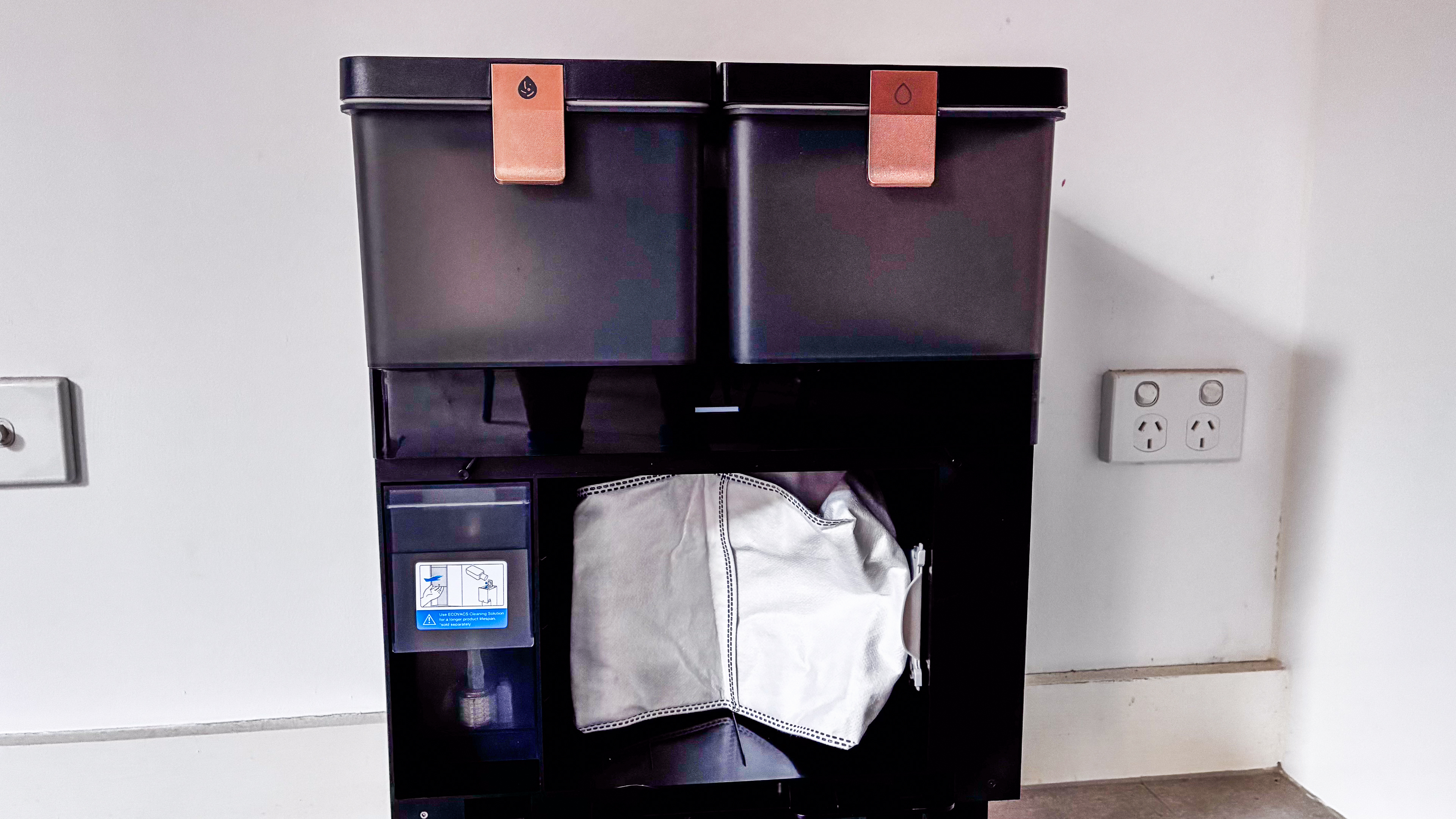 Inside the Ecovacs Deebot X8 Pro Omni base station showing the dust bag and the soap dispenser