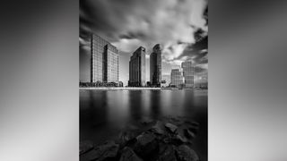 Skyline in front of the sea, with stones in the foreground and dynamic blurry clouds in the background