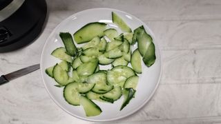 A plate of sliced cucumber in a variety of shapes and sizes