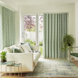 White and green living room with large window with green patterned curtains