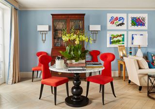 Bright red chairs with lock shape, baby blue walls with bold hanging prints