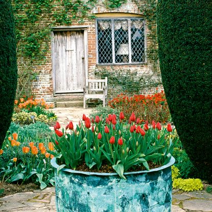 Sissinghurst knows how to get it right: red tulips in a weathered copper planter this superb Kent garden.