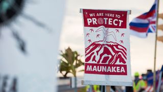 A protester displays a banner about protecting Maunakea from the Thirty Meter Telescope in August 2019.