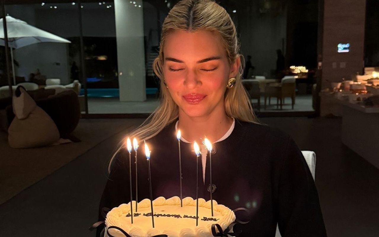 Kendall Jenner on her birthday wearing a black cardigan with chunky gold earrings.