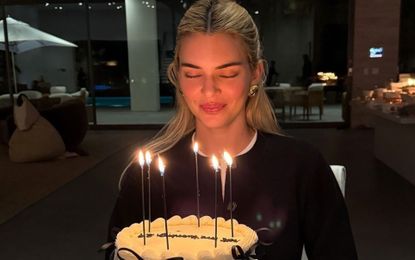 Kendall Jenner on her birthday wearing a black cardigan with chunky gold earrings.